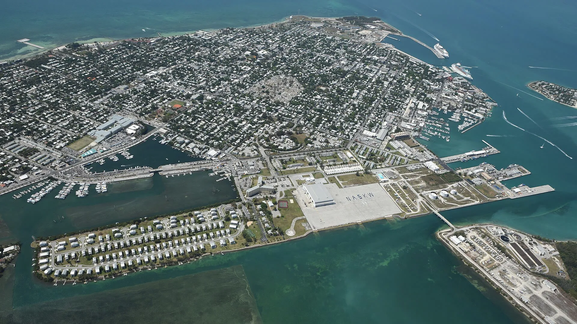 Key West from the air: Old Town and the harbour on the right, Garrison Bight and its charter docks mid-left, shallow flats in the foreground and open water beyond